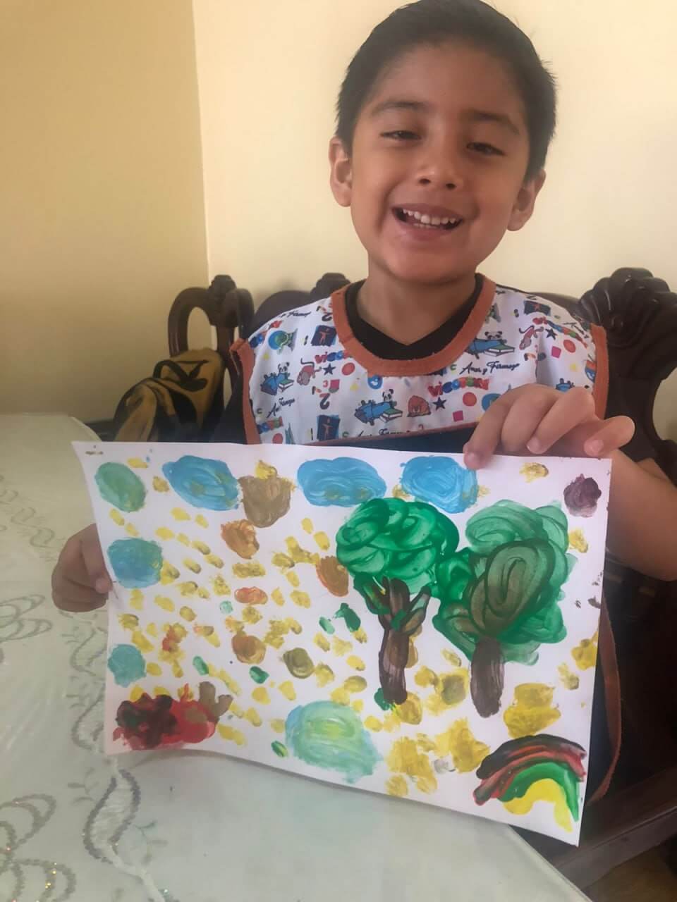 Manos infantiles pegando hojas frescas en una cartulina de colores